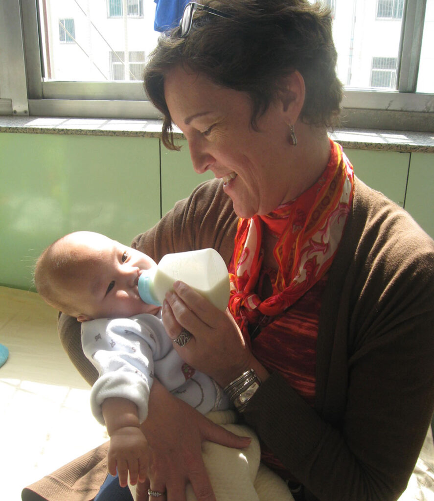 woman who helped many adopted children feeding a baby